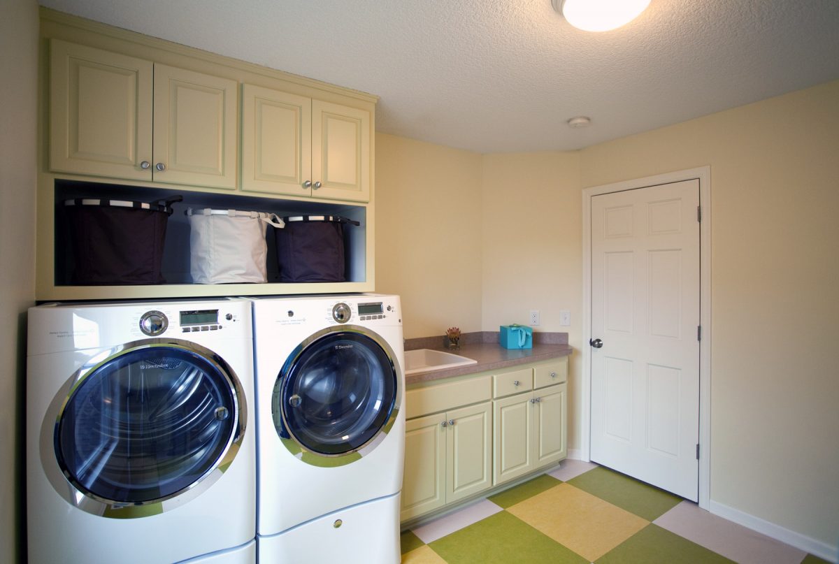 <p>For the laundry room, TreHus repurposed the original maple kitchen cabinets by painting them light green for a little added personality. Now there is room for laundry workspace, and a counter and desk area on the other side of the room for crafts.</p>
