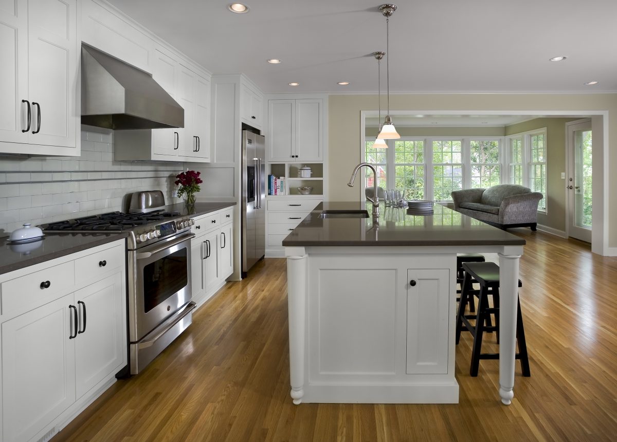 <p>The kitchen used to be at the back of the home, and is now comfortably in the center, with the new family room addition at the back.  All three exterior walls of the family room have large windows, letting in the light and adding to the spacious feel.</p>
