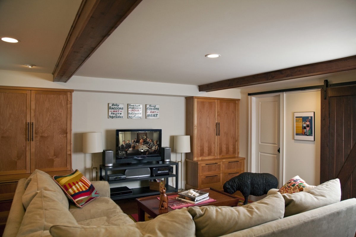 <p><span style="color: #3d3e39;">The owners of this recently finished basement are a creative and colorful couple, and we did our best to reflect their personalities in our design. Clear alder custom cabinets, a floating wood floor, and ceiling beams make the space interesting. A barn door hides a built in desk, and the staircase is painted with rainbow colors. The owners’ decor confirms the space’s funky character – notice the prominently placed black sheep…..</span></p>
