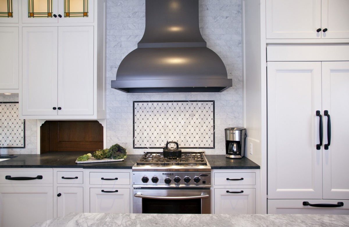 <p>This shot shows some of the thought and detail that went into the kitchen. A custom hood gives a curvy elegance to the space, while the carrera marble backsplash and soapstone countertops add a rich texture. The cabinet front fridge (right) blends seamlessly with the cabinetry, and the stained/leaded glass windows add a pop of color and tie the space in with the originals in the buffet in the dining room.</p>
