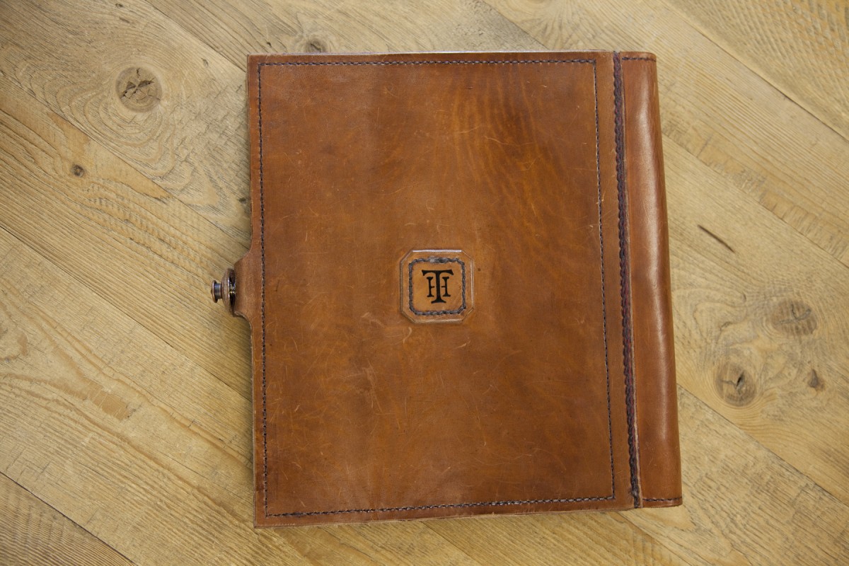 <p>On the back of the book, they were able to add our logo by lightly pressing a printing dye into a damp piece of leather, and then tracing over the indentation and hand-cutting and stitching the piece onto the back of the binder.</p>

