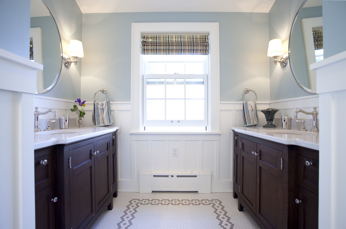 <p>This bathroom is used every morning by a busy family of six as they get ready for the day. Popping up a dormer made the bathroom much larger, and light finishes give the room a clean, cheery feeling. Details like the white painted wood wainscoting and rug inlay add visual interest, while the dueling vanities make it easy for several people to get ready for the day simultaneously.</p>
