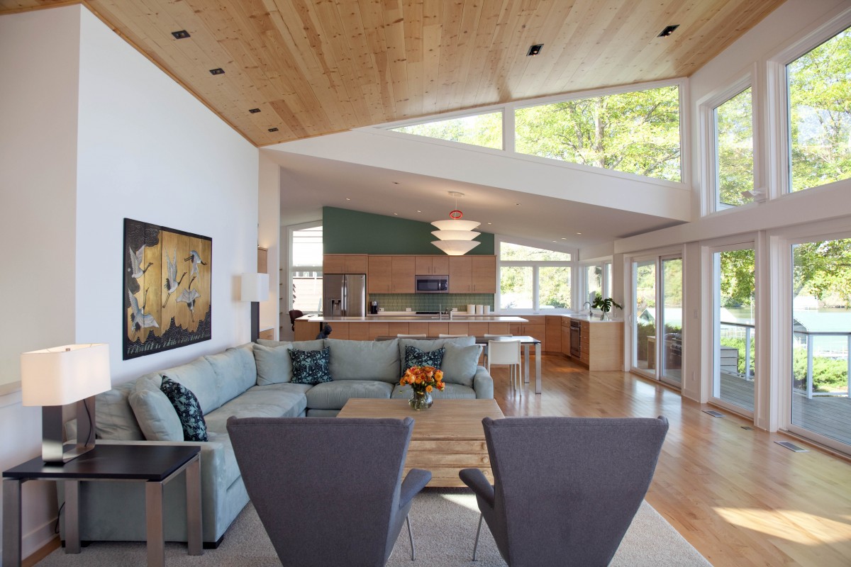 <p>The home’s modern butterfly roof leads to a spectacular wall of windows, beckoning guests to sit and enjoy the view. A wall was removed, opening the living area to the kitchen.</p>
