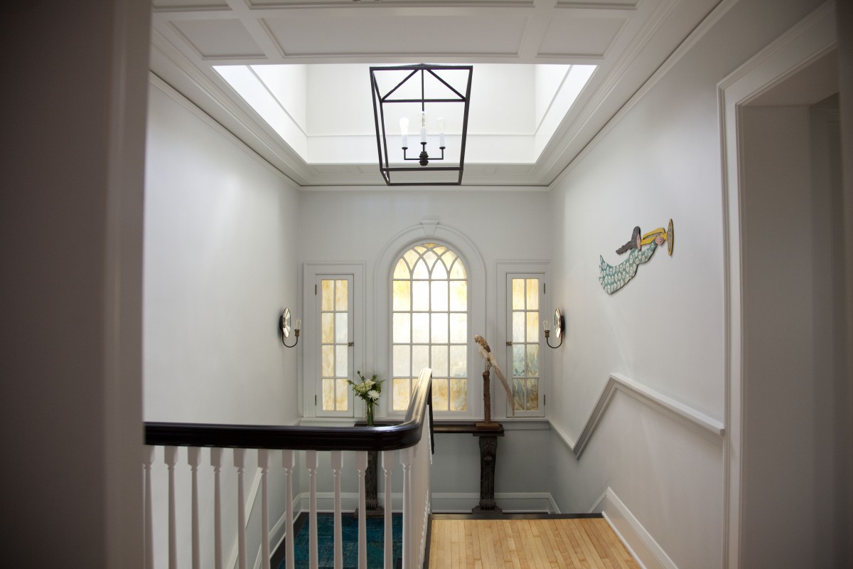 <p>Opening the floor beneath a dormer at the main stairwell increased the amount of daylight coming into the house. A paneled ceiling was created to highlight and frame the new opening to the dormer above.</p>

