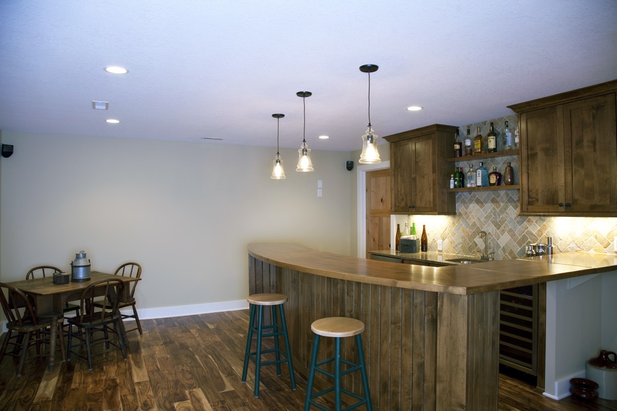 <p>The basement wetbar is a great place guests and family members to congregate. The material selections create a warm, high-end but unpretentious feel in this room – the bar and cabinets are clear alder, the floor is hand-scraped acacia, and the backsplash is a quartzite tile.</p>
