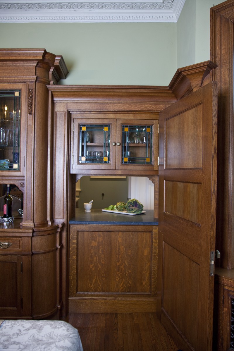<p>Before this project, there was a sheet of plywood behind the door. TreHus designed and built this pass-through from the kitchen to seamlessly match the rich, ornate buffet original to this 100+ year old home.  The graining, detailing and stain of the new quartersawn oak cabinet and the detailing and coloring of the new leaded glass doors match the originals exactly.</p>
