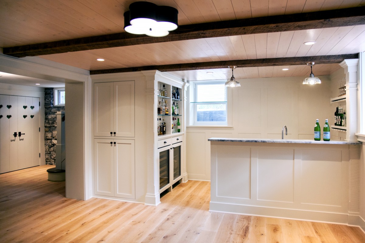 <p>The electrical and pipes had to be moved so the space could be used as a living area. The finished basement was built with a heated oak floor, pine tongue-and-groove paneling and reclaimed barn wood for the ceiling beams. Unique deep storage drawers take advantage of unused space under the staircase.</p>

