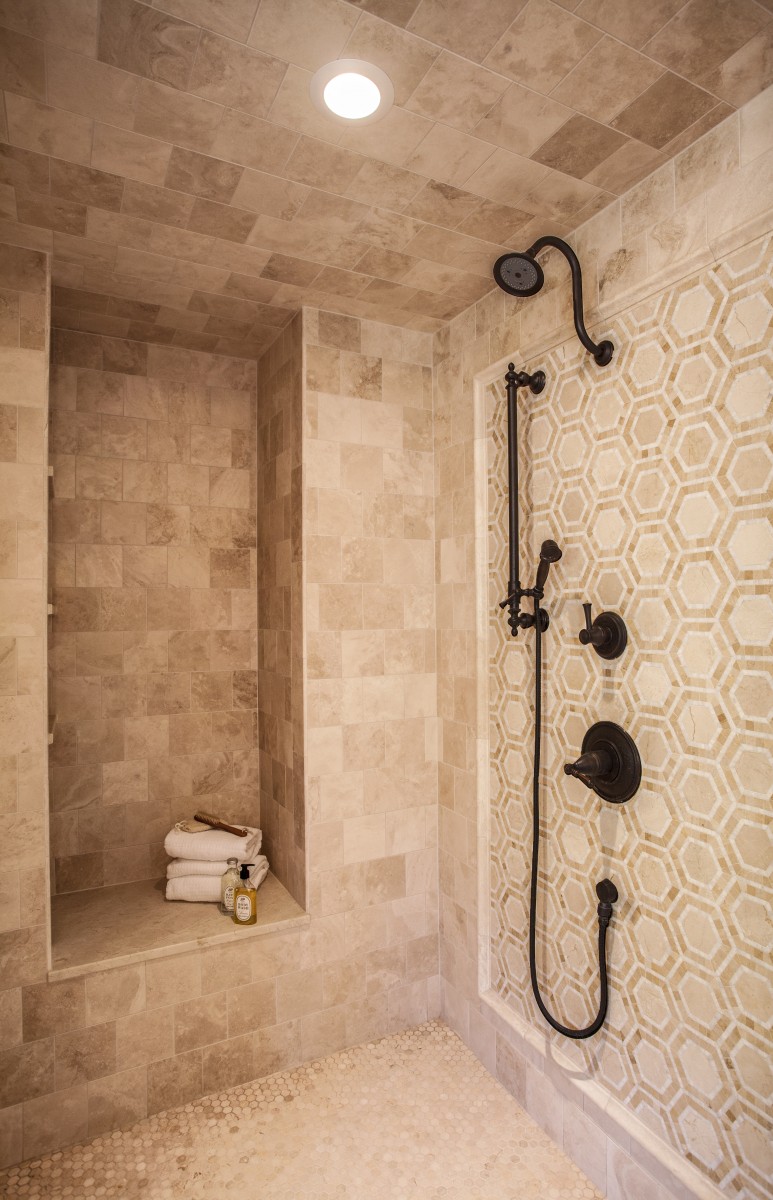 <p>The frameless shower is adorned with antique bronze bath accessories and unique mosaic tiles.</p>
